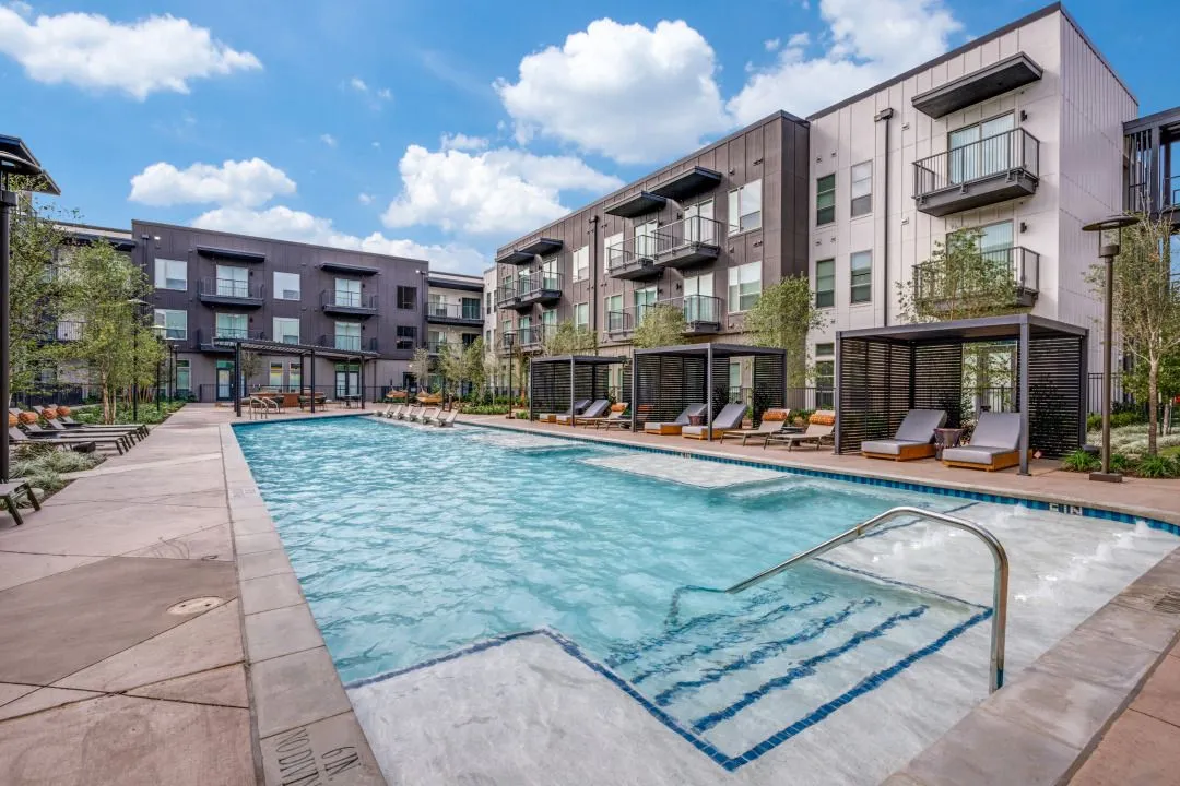 Swimming pool with seating and view of apartment building