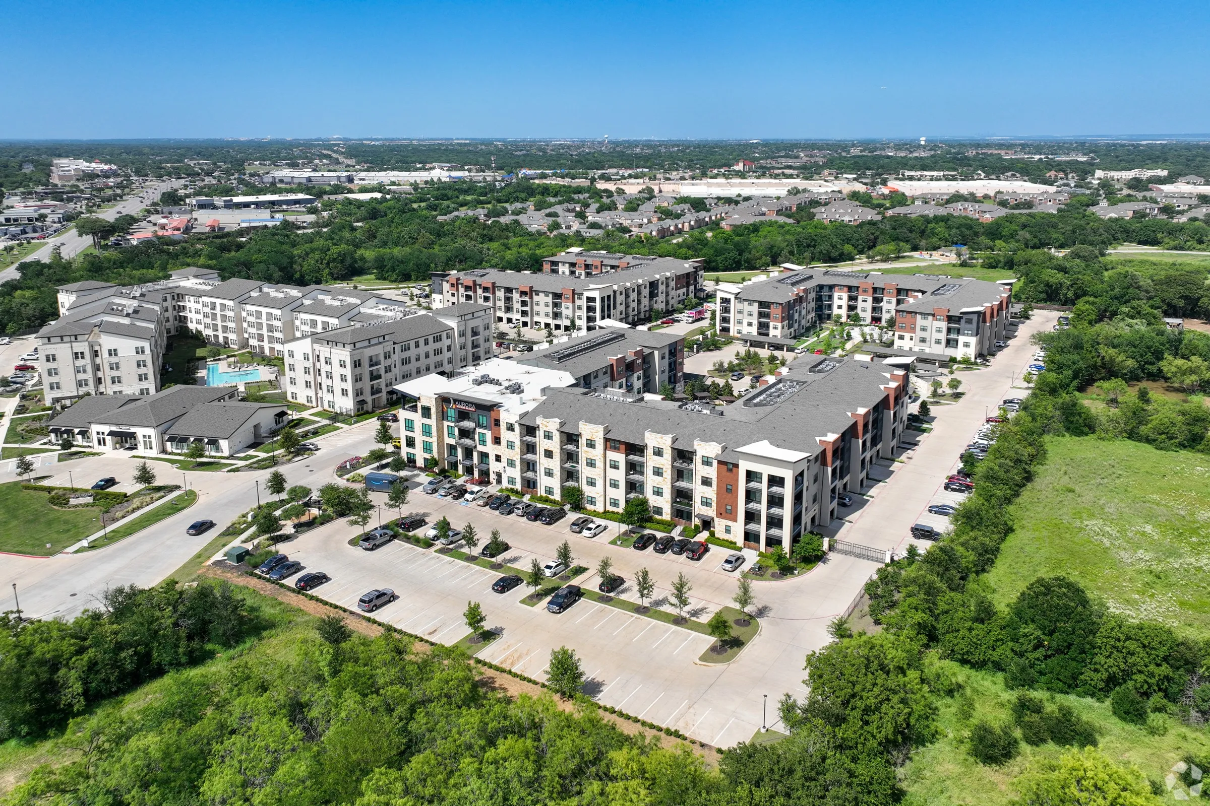 A bird's eye view of a large apartment complex surrounded by greenery and roads