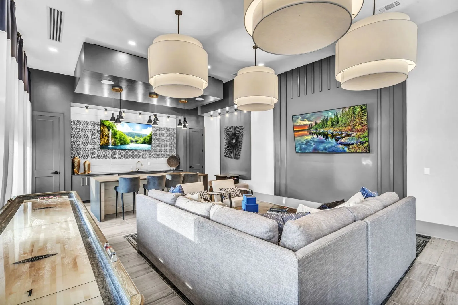 A modern living room with a grey couch and a pool table. at Axis Grand Crossing