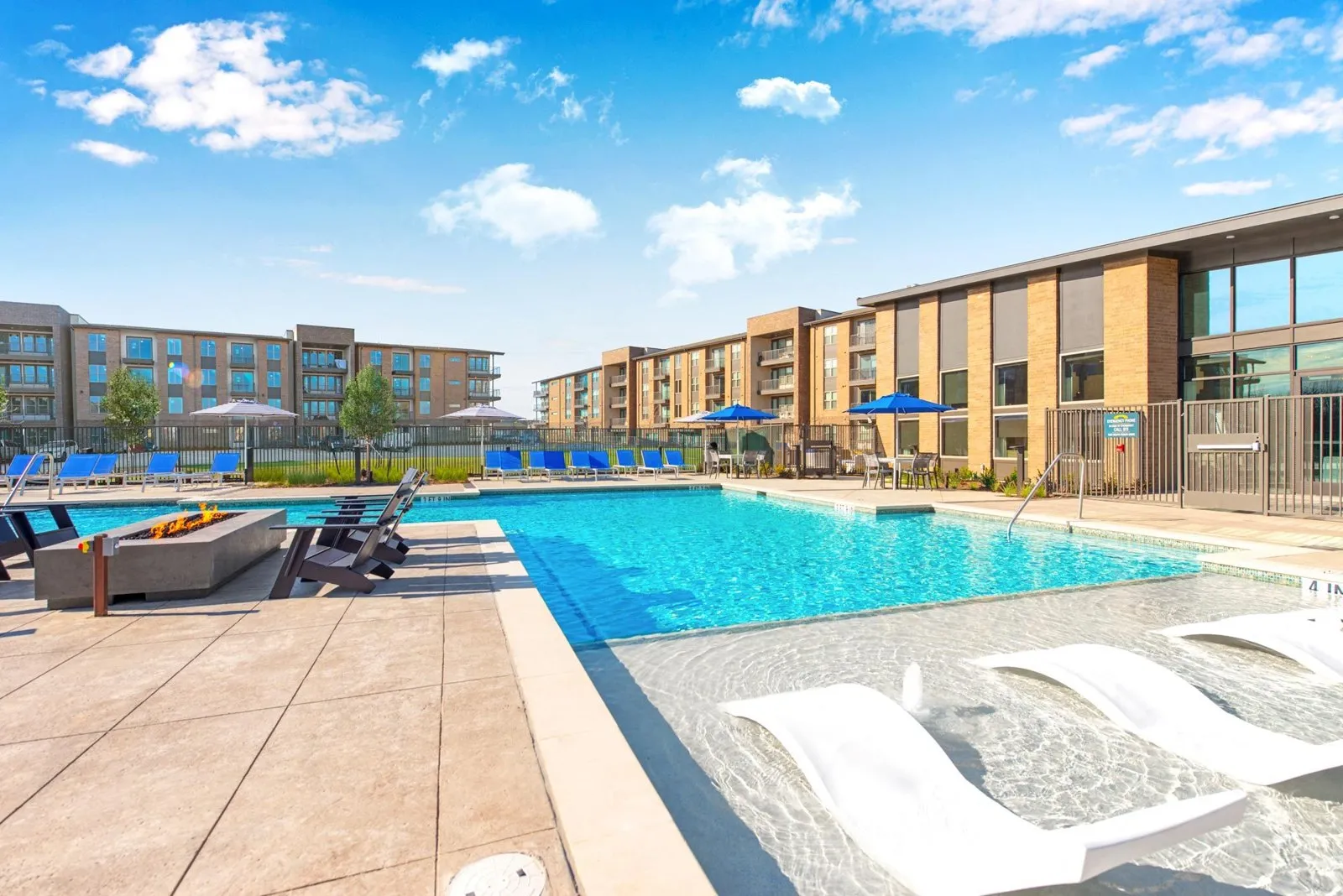 A swimming pool with sun loungers and apartment buildings in the background. at Axis Grand Crossing