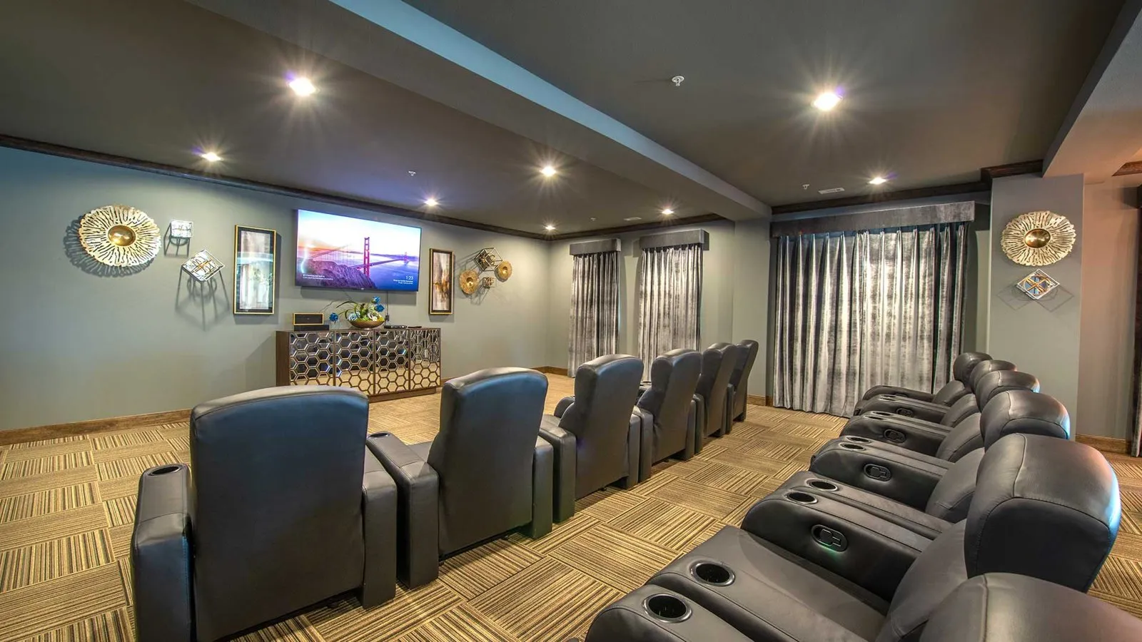 Two rows of luxury movie theater seats sit before a large screen on the left. at Bell Tower Reserve