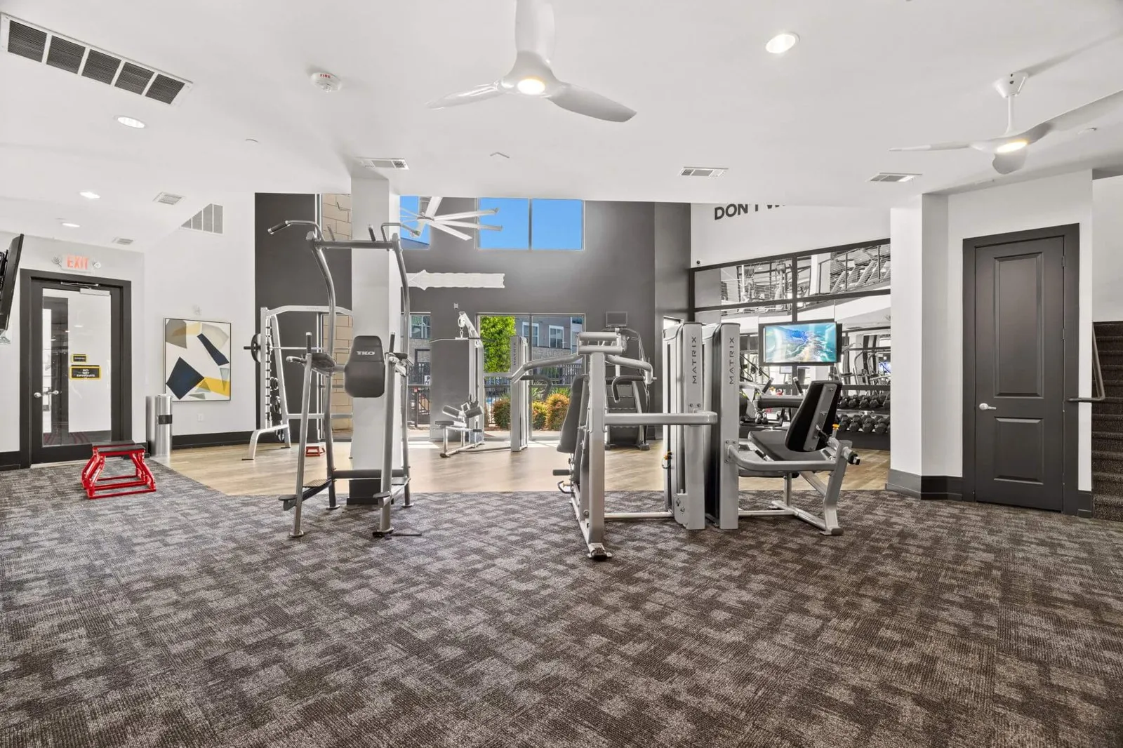 A gym with a variety of equipment including treadmills, weights, and a squ at Axis at Watters Creek
