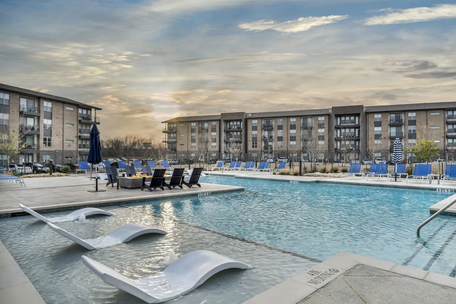 A swimming pool with a slide and loungers in front of apartment buildings. at Axis Grand Crossing