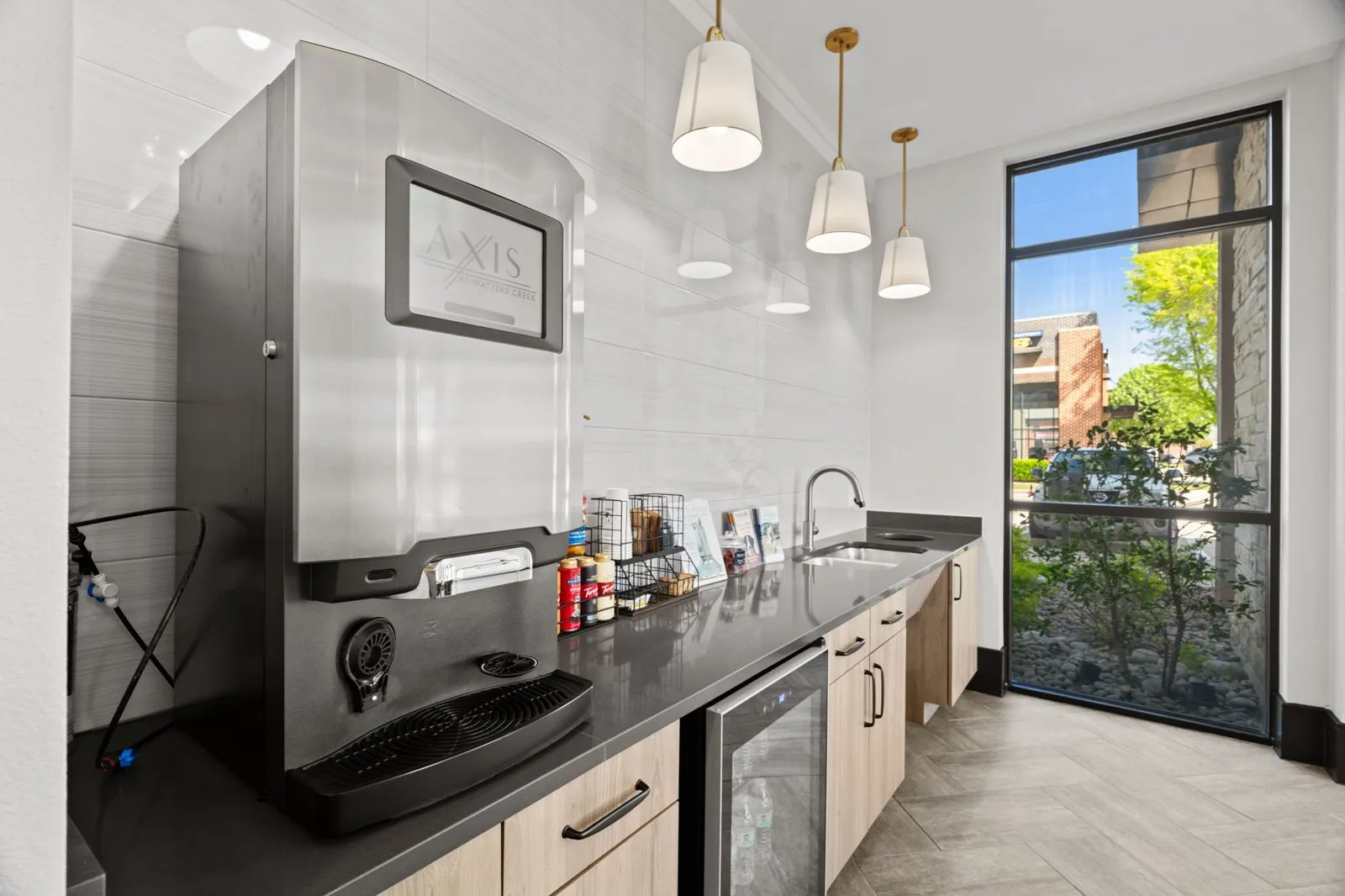 A modern kitchen with a large window overlooking a tree. at Axis at Watters Creek