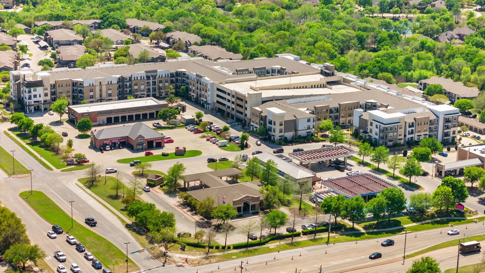 A large apartment complex with a parking lot in front. at Axis at Watters Creek