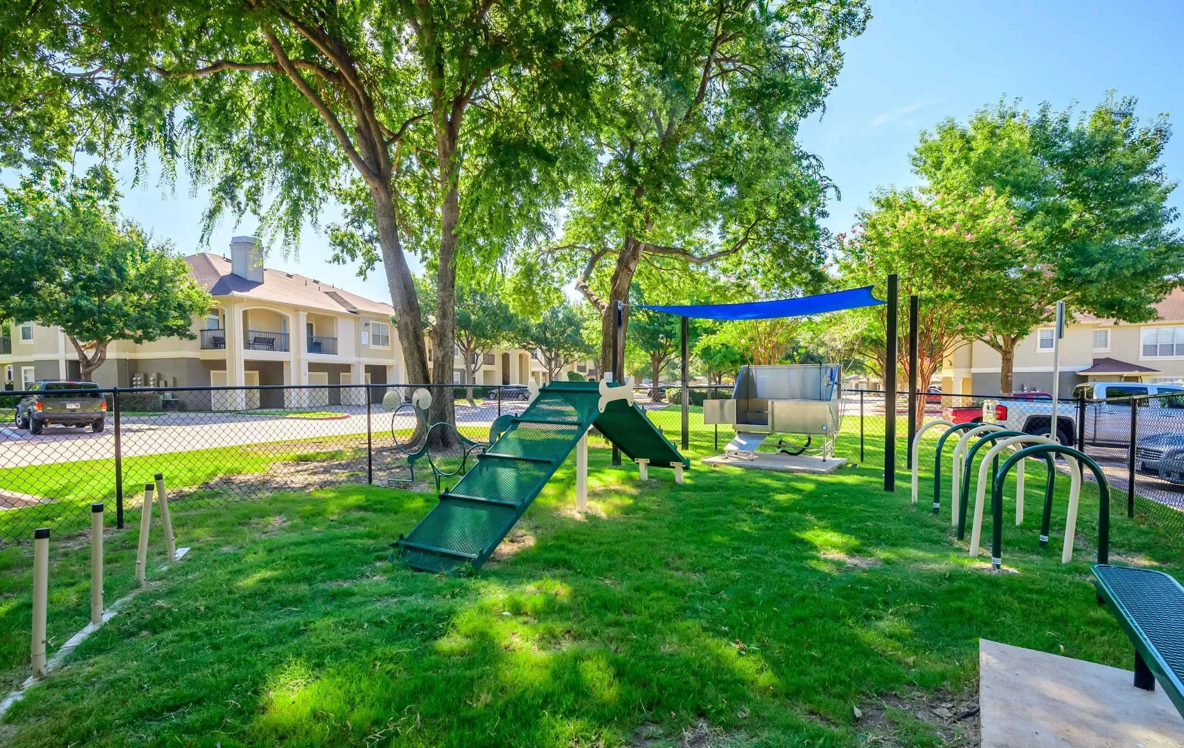 23Hundred at Ridgeview - A playground area with slides, a climbing structure, and shaded seating surrounded by green grass