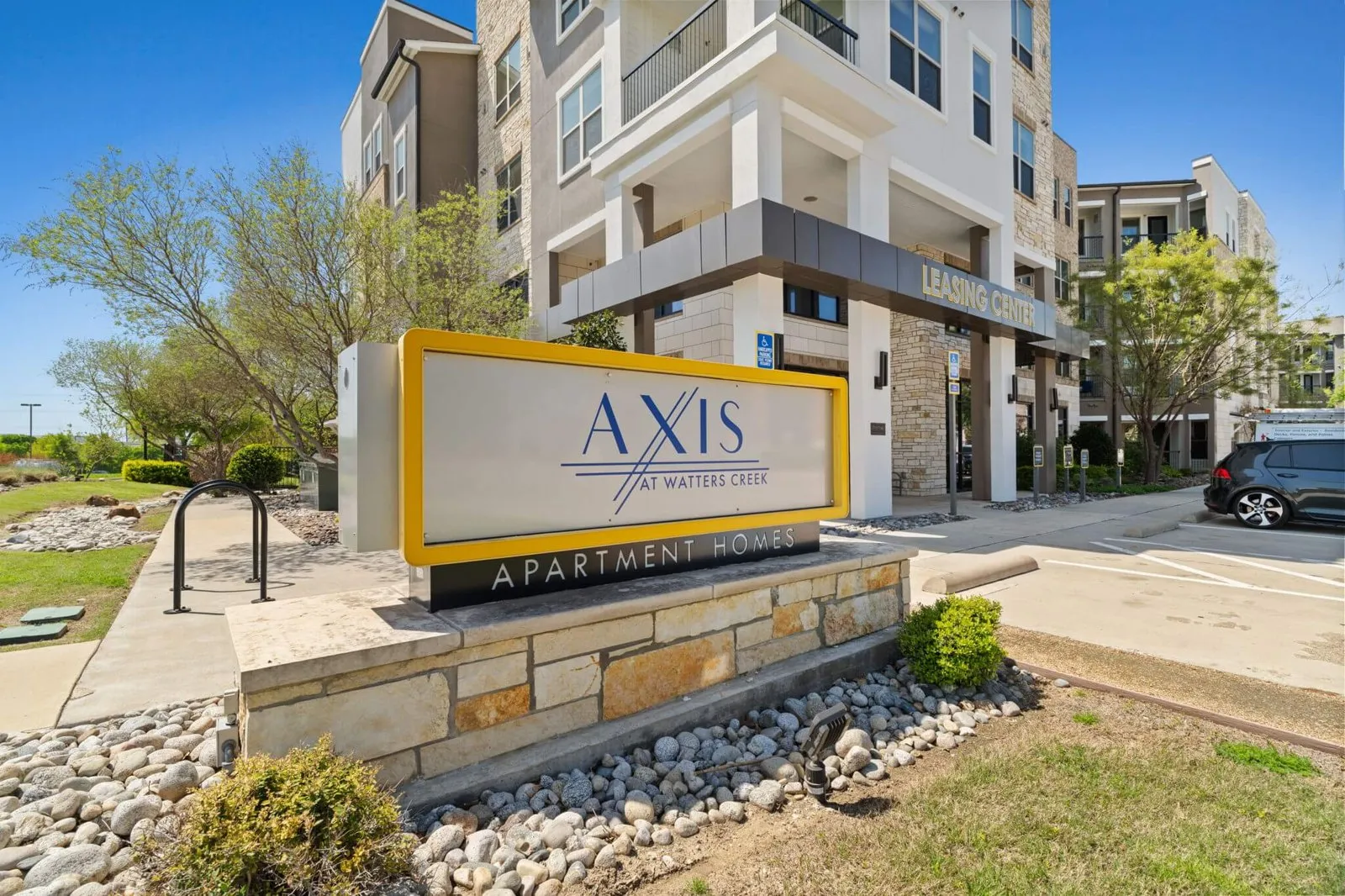 A sign for Axis Apartments in front of a building. at Axis at Watters Creek