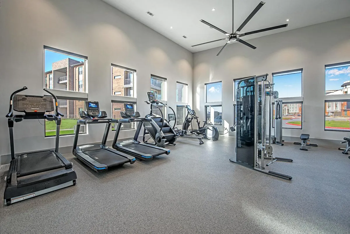 A spacious gym with treadmills, elliptical machines, and a fan. at Axis Grand Crossing