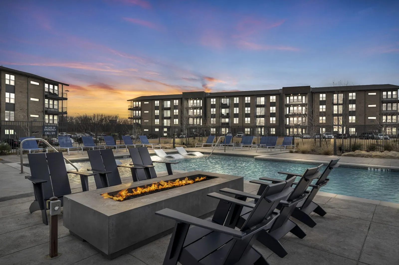 A poolside area with chairs and a fire pit in front of a building. at Axis Grand Crossing