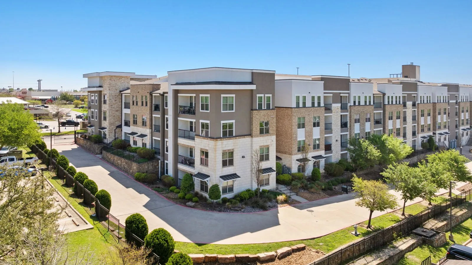A large apartment complex with a parking lot in front. at Axis at Watters Creek