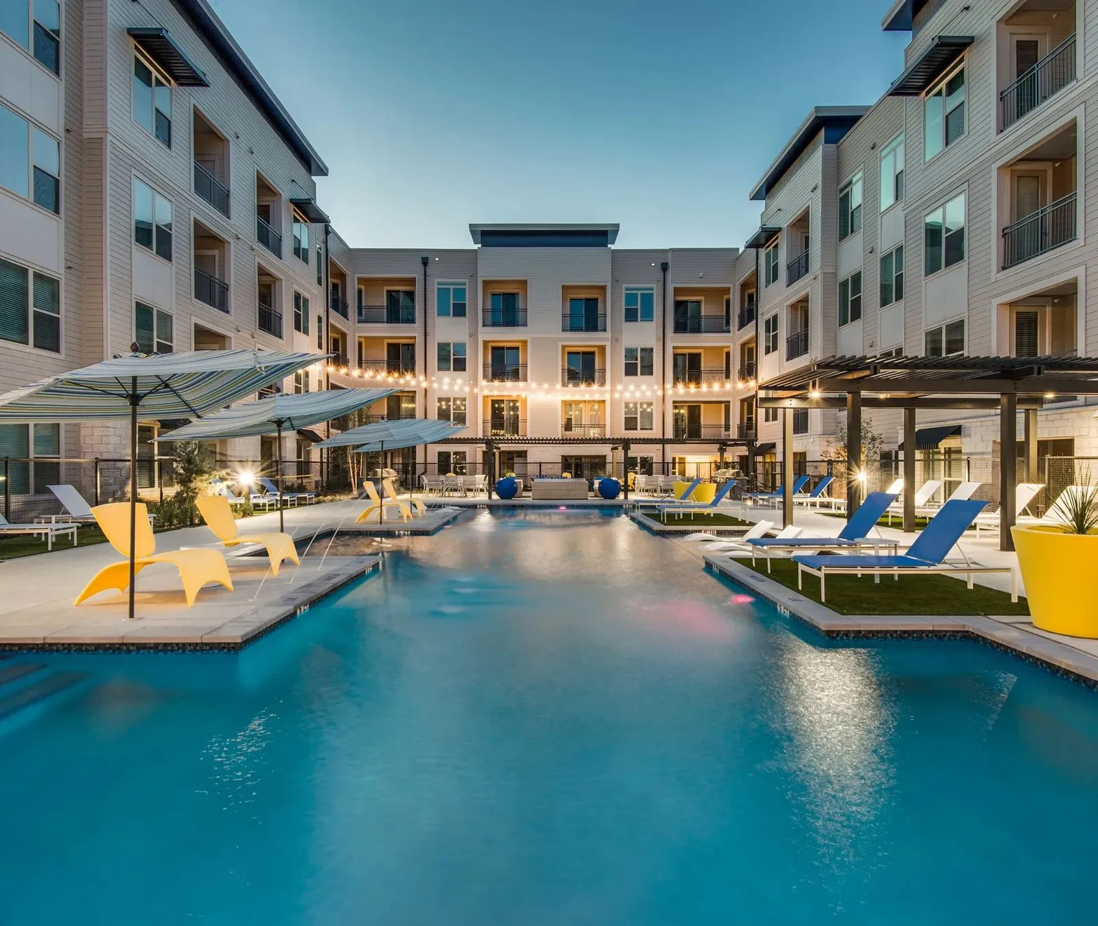 Swimming pool with cabanas and seating at Bevan Apartments at Trophy Club