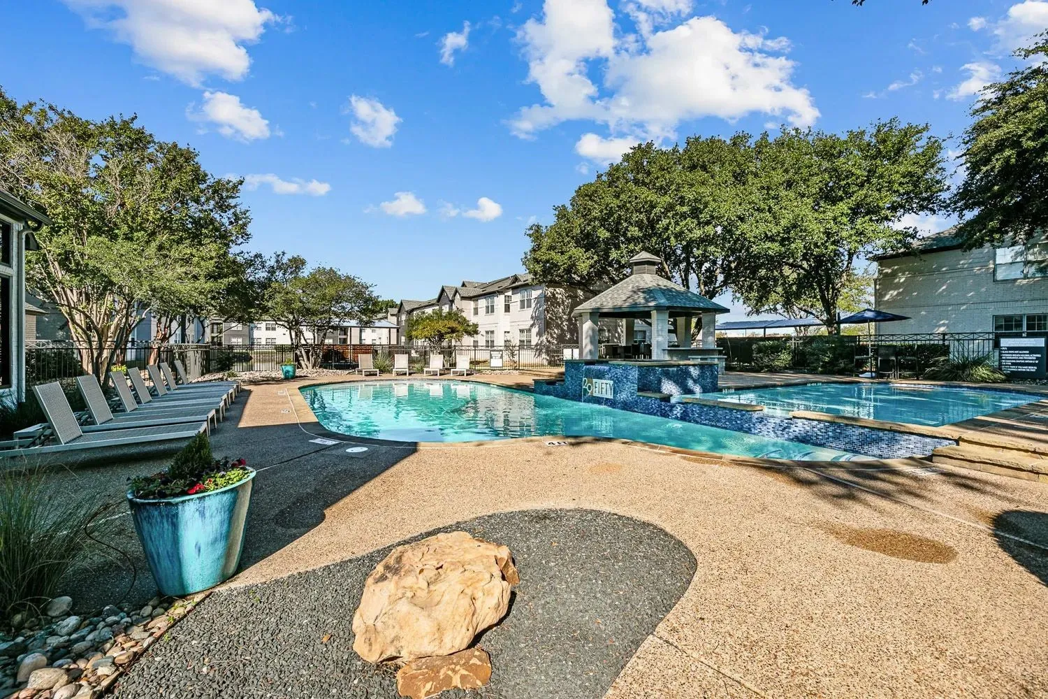 Swimming pool with sun loungers and shade trees at 29Fifty