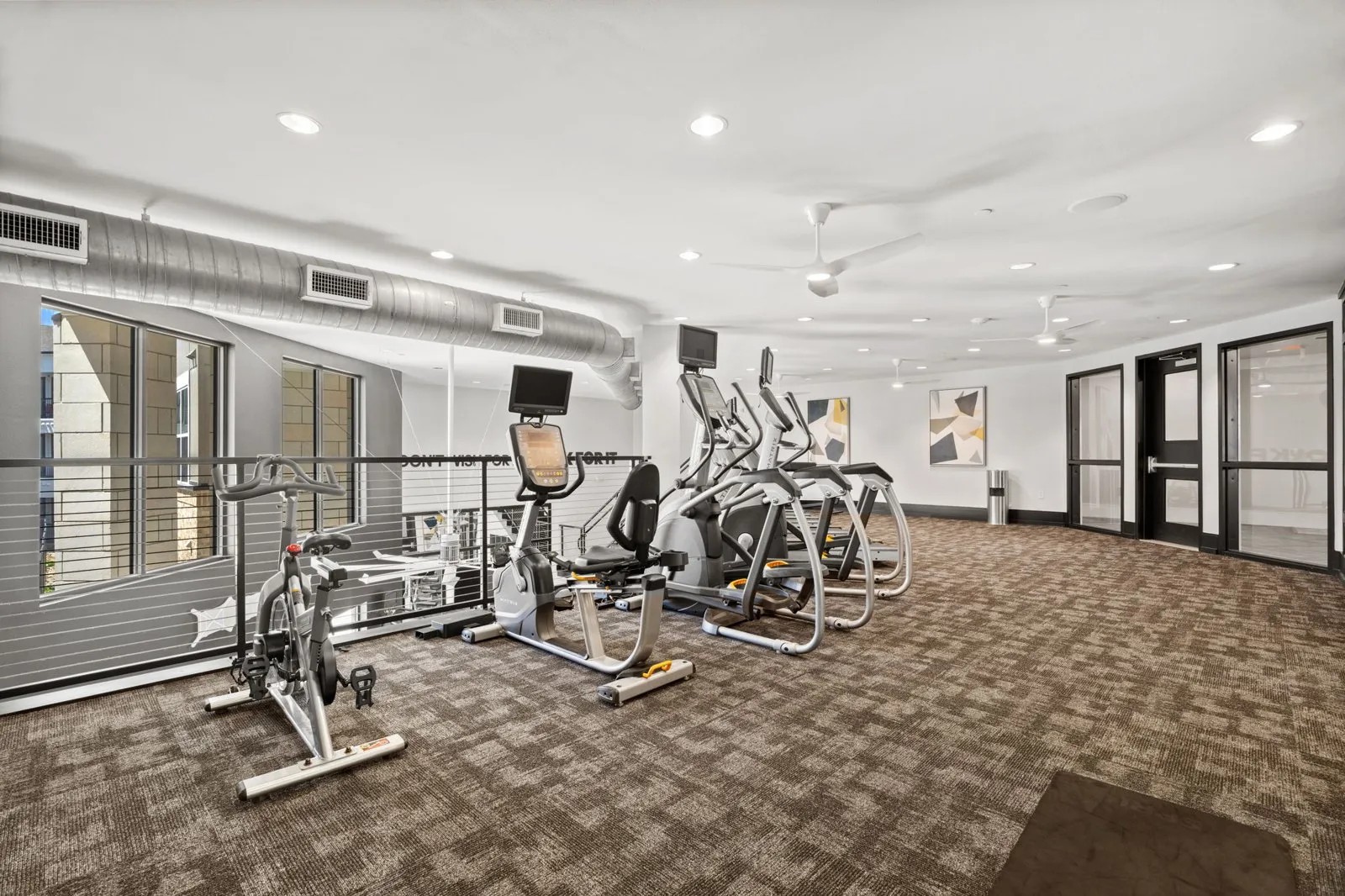 A gym with a variety of exercise equipment including treadmills, stationary bikes, and weight machines. at Axis at Watters Creek