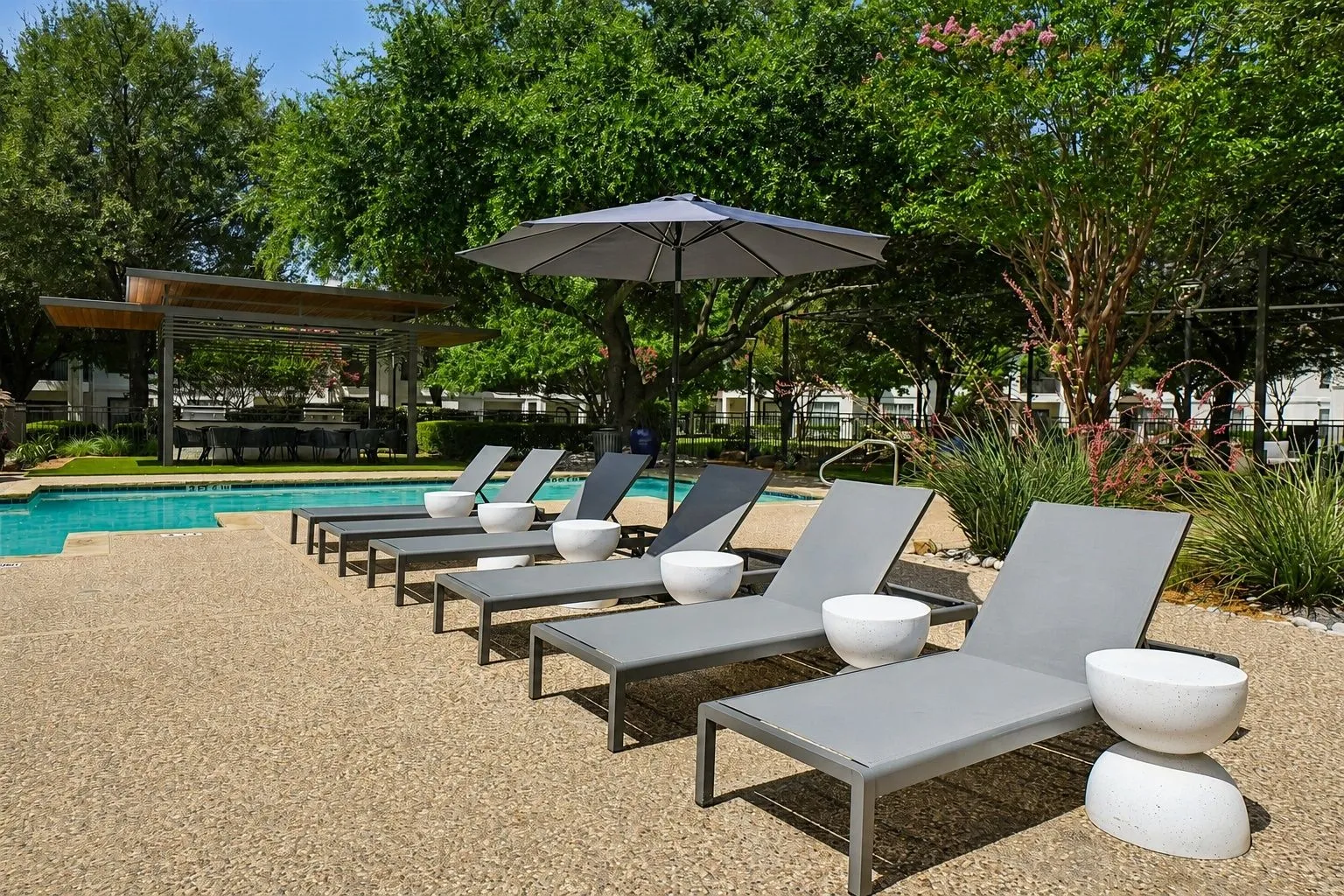 23Hundred at Ridgeview - Lounge chairs by a pool surrounded by trees and an umbrella