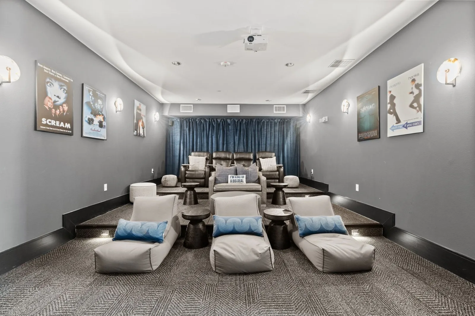 A room with grey walls and a carpeted floor has a row of white chairs with blue pillows. at Axis at Watters Creek